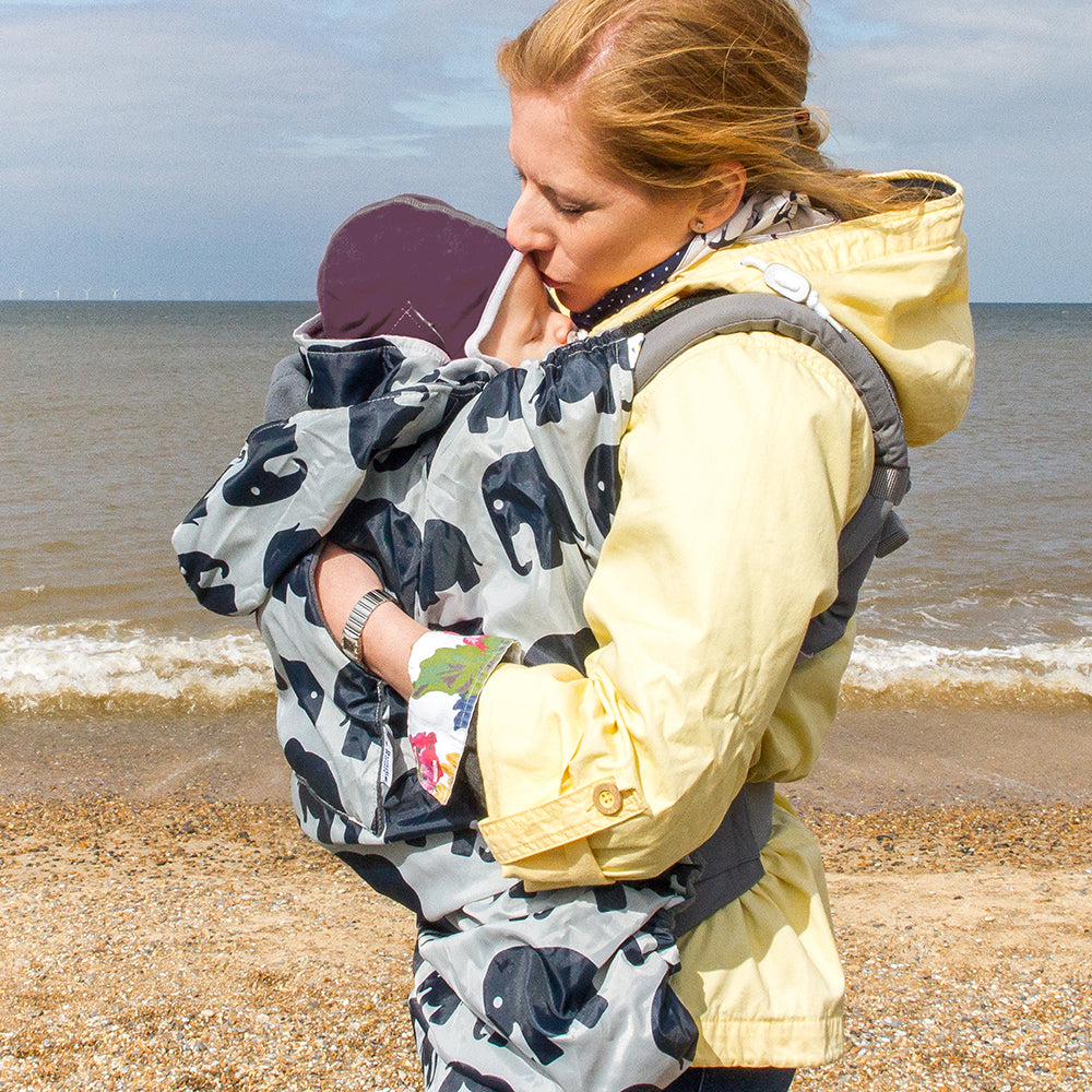 Keeping baby cosy on the beach in BundleBean Babywearing fleece-lined and waterproof cover in elephant design