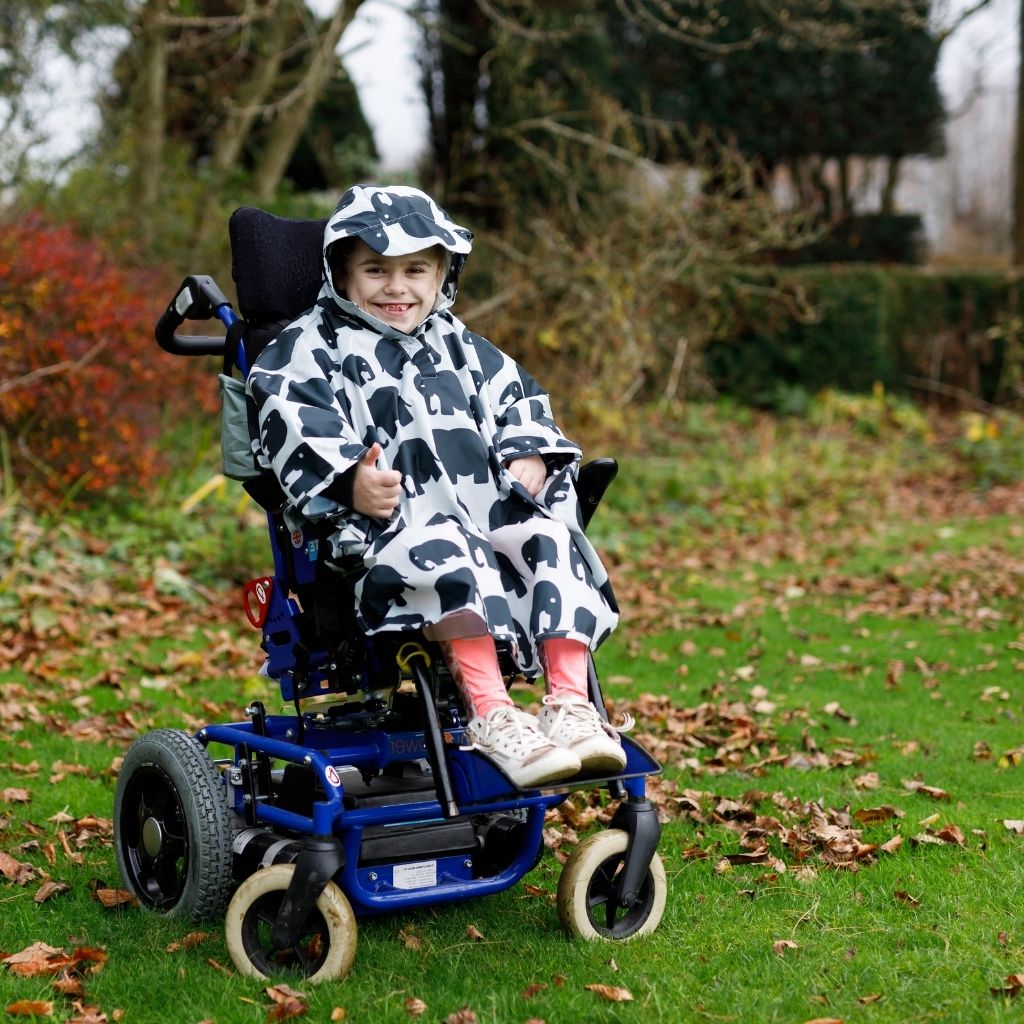 Kids Wheelchair poncho - easy to put on, fully waterproof and with peaked hood to protect faces from the rain. Seen here in an elephant design.
