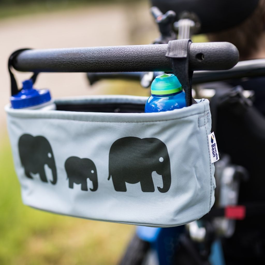 These handy wheelchair organiser bags fit on all wheelchairs, powerchairs, special needs buggies and rollators. Seen here in an elephant design. and holding two water bottles.