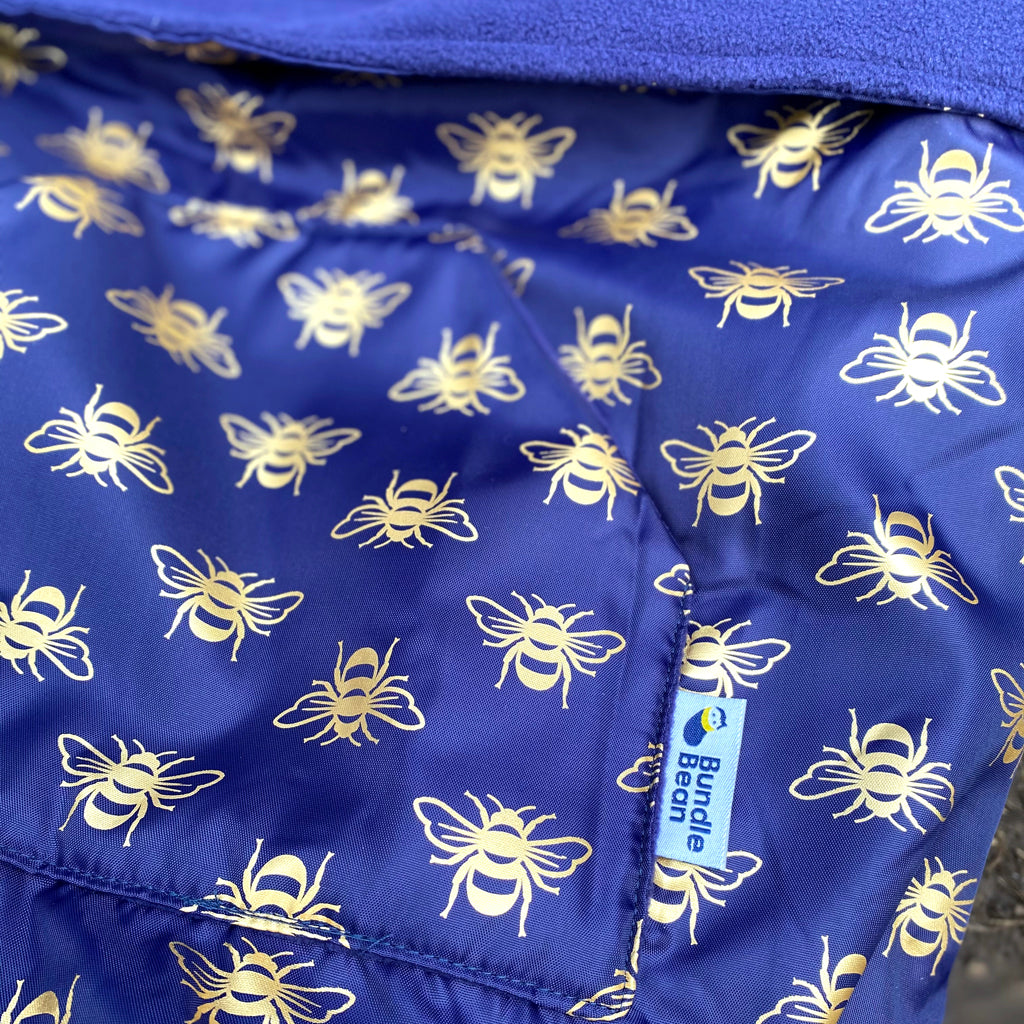 The BundleBean GO is a waterproof footmuff for babies and toddlers that fits snugly on to buggies, bike seats, car seats and baby carriers. Seen here in a bee design
