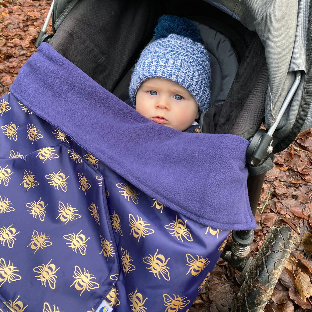 The BundleBean GO is a waterproof footmuff for babies and toddlers - seen here in a bee design and fitting on to a buggy.