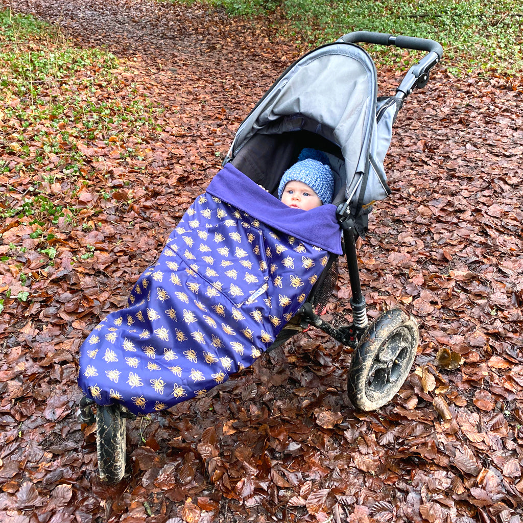 The BundleBean GO is a waterproof footmuff for babies and toddlers that fits snugly on to buggies, bike seats, car seats and baby carriers. Seen here  on a pushchair in a bee design