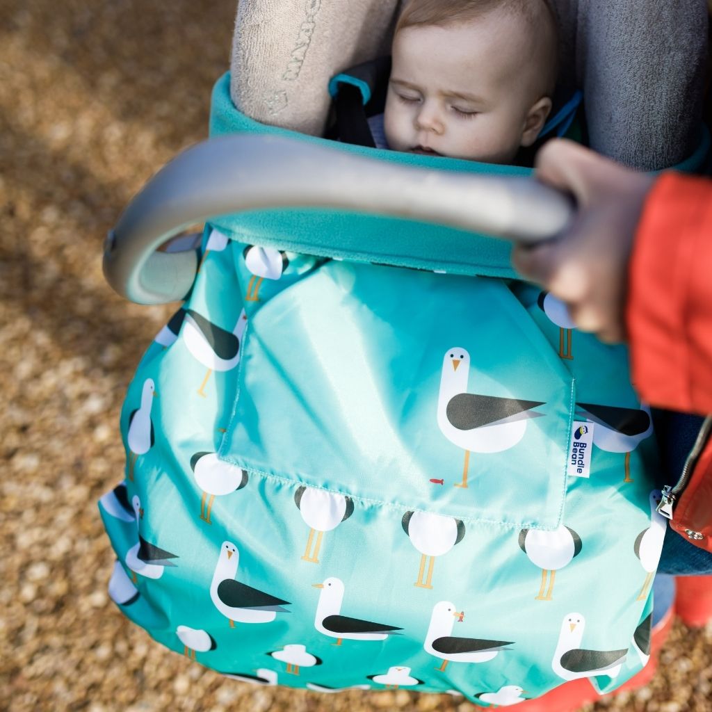 The BundleBean GO is a waterproof footmuff for babies and toddlers that fits snugly on to buggies, bike seats, car seats and baby carriers. Seen here on a car seat and in a seagull design.