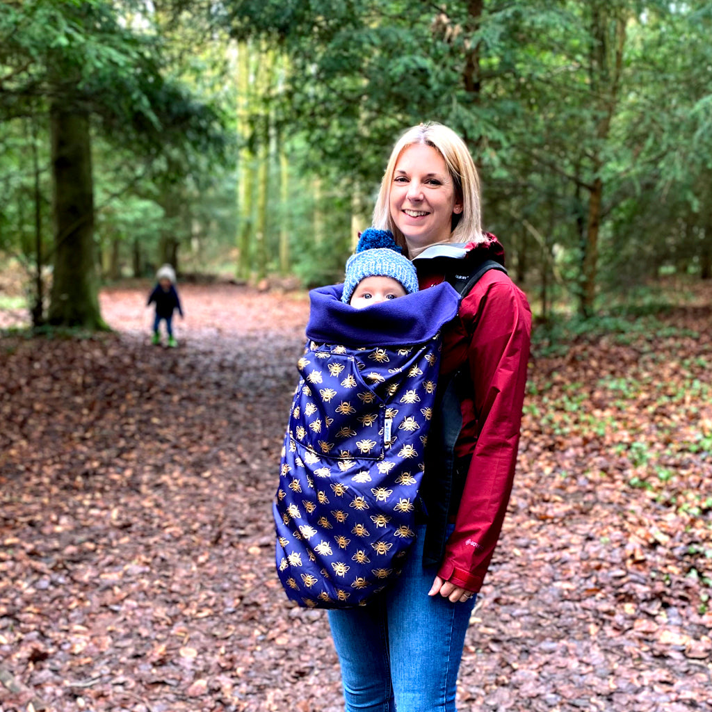 The BundleBean GO is a waterproof footmuff for babies and toddlers that fits snugly on to buggies, bike seats, car seats and baby carriers. Seen here over a baby carrier and in a bee design.