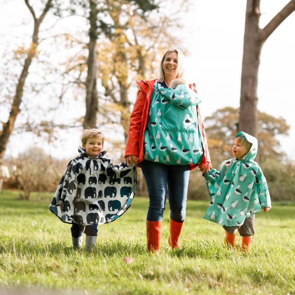 Toddler ponchos for 2-4 years old. A raincover that's easy to pop on and fully waterproof and with a peaked hood to protect little faces. Seen here in a seagull and elephant design and matching with the seagull babywearing cosy.