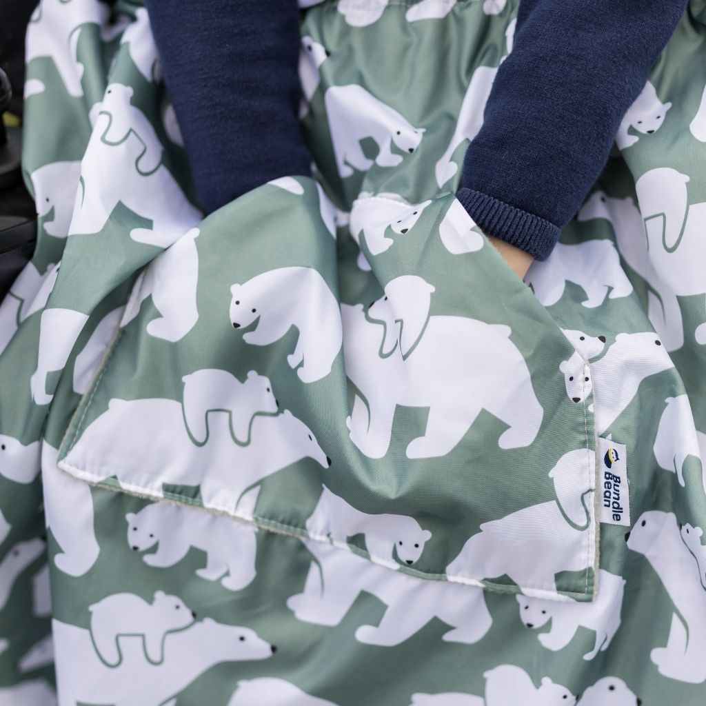Kids fleece-lined wheelchair cosies. Waterproof, warm and easy to fit. Seen here in a polar bear design. and showing the hand warming pocket.