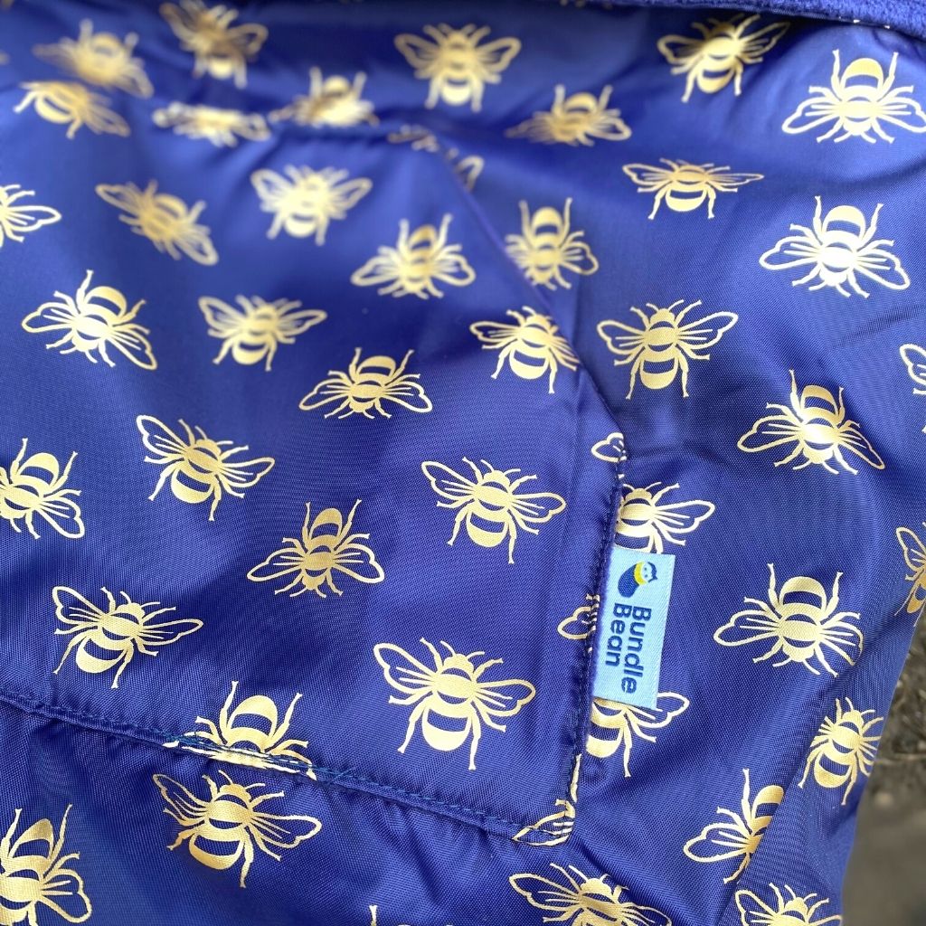 Kids fleece-lined wheelchair cosies. Waterproof, warm and easy to fit. Seen here in a gold bee design showing the hand warming pocket.